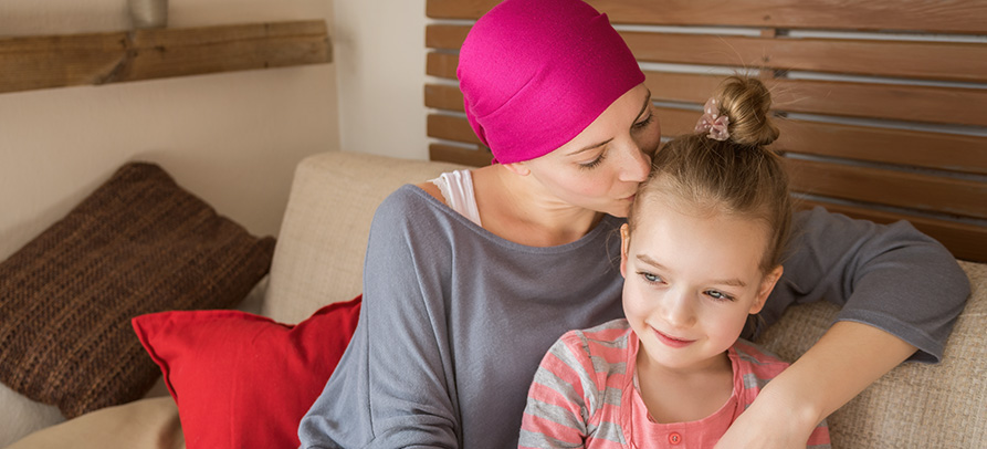 A cancer patient kisses her daughter on the head
