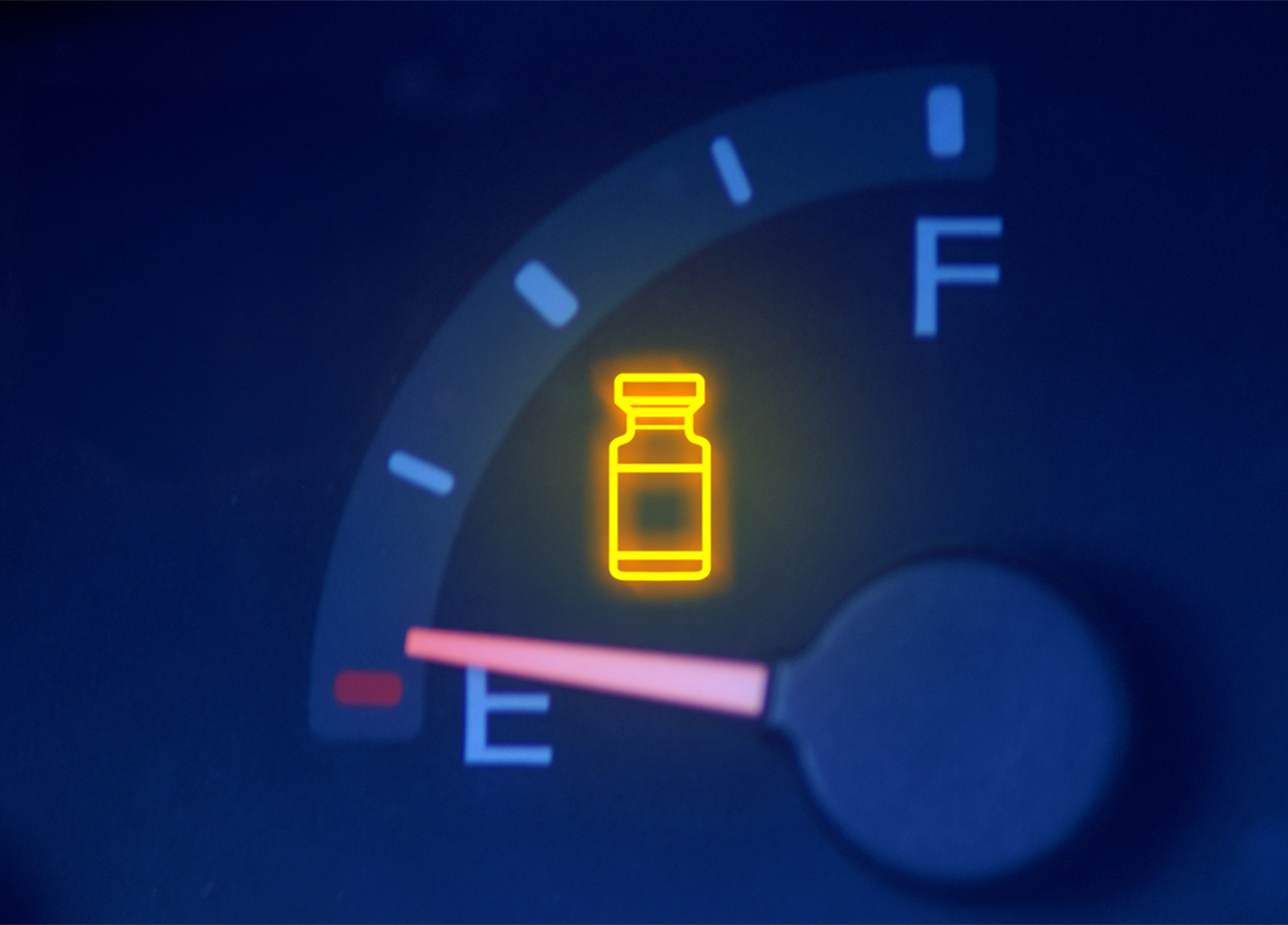 A fuel gauge, the warning light is illuminated and shaped like a medicine vial
